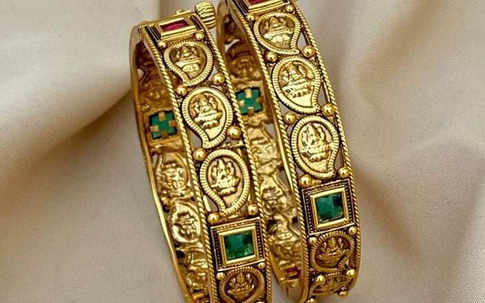 A pair of antique bangles adorned with emerald stones